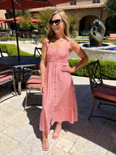 Woman in a red and white striped dress standing outdoors in a courtyard.