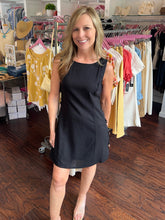 Woman wearing black linen sleeveless dress standing in a clothing store.