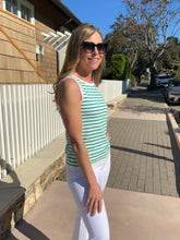 Woman in a striped shirt and sunglasses standing on a sidewalk next to a house.