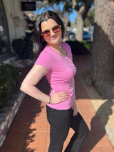 Woman in a lilac shirt and sunglasses standing outdoors on a sunny day.