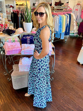 Woman wearing a blue printed maxi dress standing in a clothing store.