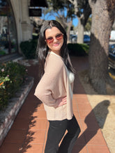 Woman wearing sunglasses and a natural cardigan on a sidewalk