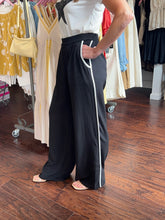 Person wearing black pants standing in front of a clothing rack.