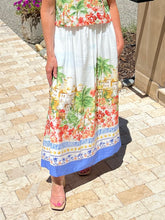 Person wearing a colorful skirt with a tropical print on a paved walkway.