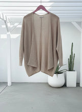 Natural cardigan on a hanger with plants in the background