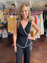 Woman wearing a black wrap tank standing in a store.