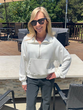 Woman wearing a white jacket and sunglasses outdoors on a patio