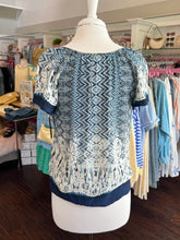 Blue and white patterned top showing back view on a mannequin in a clothing store.
