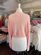 Pink knitted sweater on a mannequin in a store setting