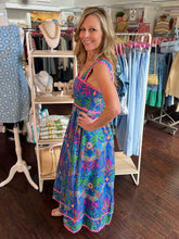 Woman in a colorful dress standing in a clothing store.