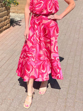 Person wearing a pink floral dress on a paved surface