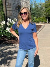 Woman wearing a blue shirt and sunglasses outdoors on a sunny day.