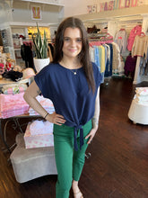 Woman wearing a short sleeve navy blouse standing in a store.