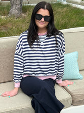 Woman wearing a striped sweater and sunglasses sitting on a couch outdoors.
