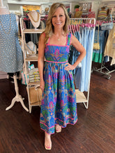 Woman in a colorful dress standing in a clothing store.