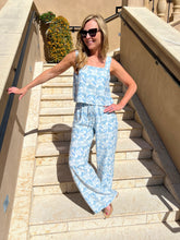 Woman in a blue floral outfit standing on stone steps outdoors.