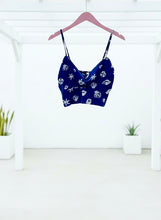 Navy seashell print top with white patterns on a hanger against a white background