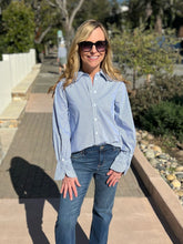 Woman wearing a blue and white striped shirt and sunglasses outdoors.