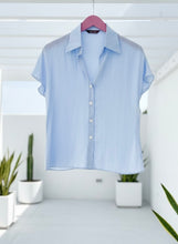 Halogen blue button top on a hanger against a white background.