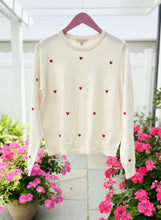 White sweater with red hearts patterns on a hanger. 