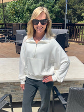 Woman wearing a white jacket and sunglasses outdoors on a patio