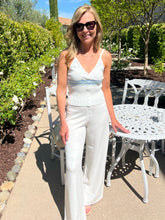 Woman in a white outfit standing outdoors near garden furniture