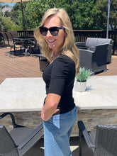 Woman wearing sunglasses and a black top outdoors on a patio