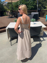 Woman in a striped dress standing on a patio with outdoor furniture and plants.