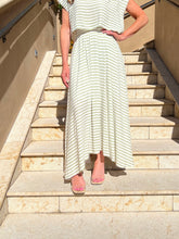Person wearing a white and gray striped dress standing on stone steps.