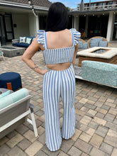 Woman in a blue and white striped outfit standing on a patio.