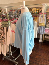 Light blue open back sweatshirt on a mannequin in a clothing store setting