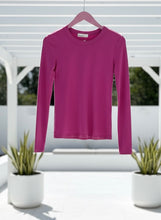 Fuchsia long-sleeve shirt on a hanger with a blurred outdoor background