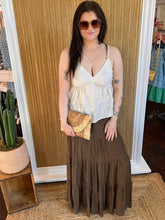 Woman in a white top and brown skirt holding a clutch in a store setting.