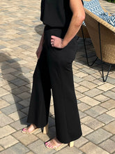 Person wearing a black outfit standing on a paved patio