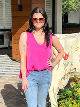 Woman wearing a pink top and blue jeans standing outdoors.