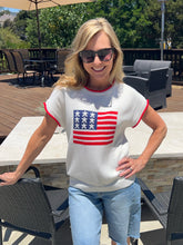 Woman wearing a white t-shirt with an American flag design outdoors.