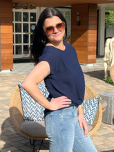 Woman in navy top and jeans standing outdoors with a building in the background