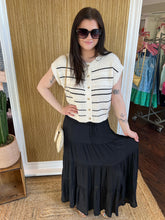 Woman wearing a white and black striped sweater and black skirt in a store setting.