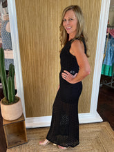 Woman in a black dress standing in front of a wall in a store.