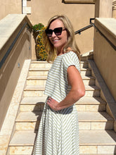 Woman in a striped dress standing on stone steps outdoors