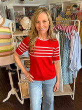 Woman wearing a red and white striped shirt in a clothing store.