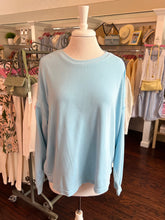 Light blue open back sweatshirt on a mannequin in a clothing store setting