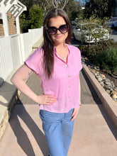 Woman wearing a lilac top and sunglasses outdoors on a sunny day.