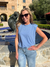 Woman wearing stripe blue top and jeans standing in front of a pool.