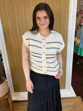 Woman wearing a white and black striped cardigan with a neutral background