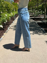 Person wearing light blue jeans and a white top in a garden setting