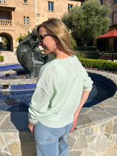 Woman standing by a pool with a fountain in an outdoor setting