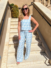 Woman in a blue patterned outfit standing on stone steps outdoors.