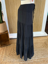 Black tiered skirt worn by a person, standing against a wooden panel wall.