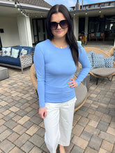 Woman in a blue shirt and white pants standing on a patio
